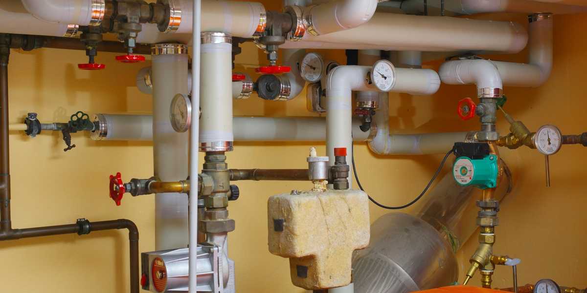 Pipes and valves around a water heater in a utility room