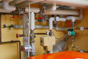 Pipes and valves around a water heater in a utility room