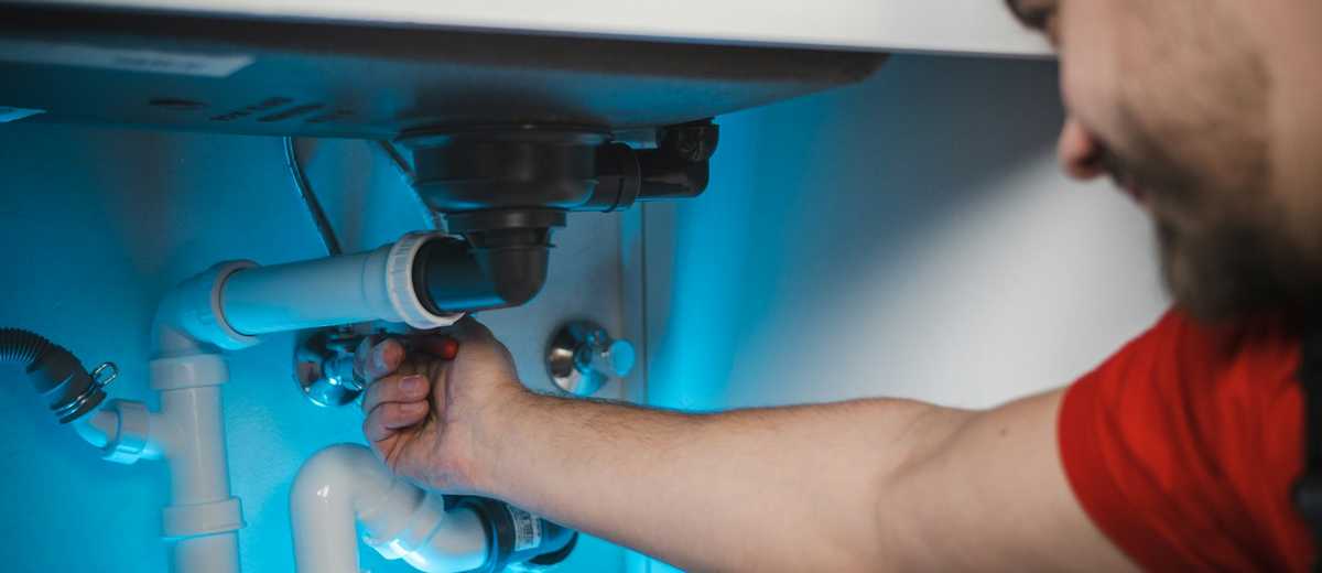 A plumber clearing the trap under a bathroom sink