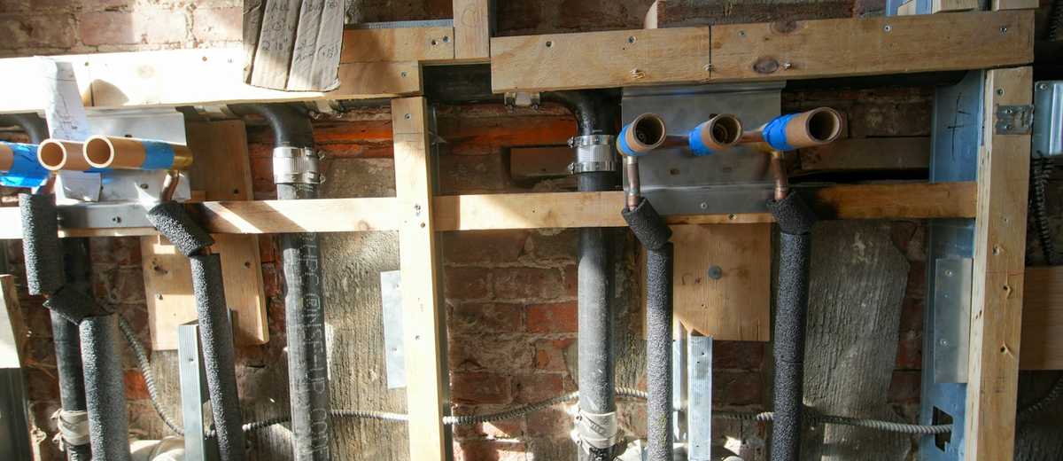 Copper and plastic water lines inside an opened wall