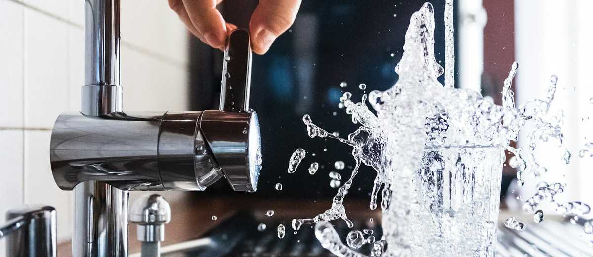 Water splashing from a kitchen tap into a steel sink